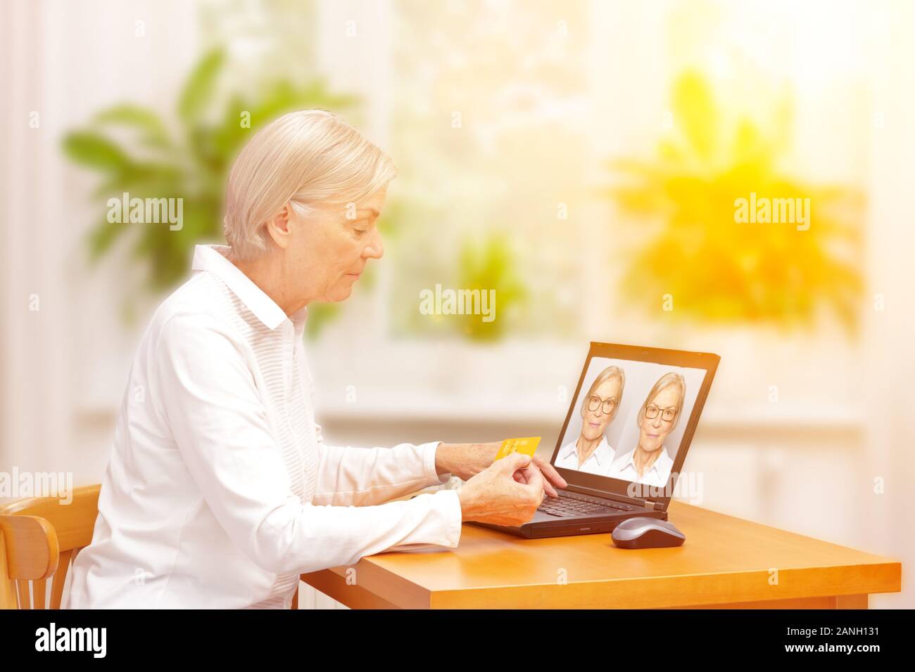 Shopping eyeglasses online concept: senior woman paying for her new glasses at home in her living room. Stock Photo