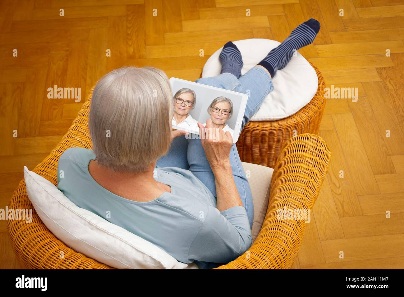Shopping eyeglasses online concept: senior woman choosing her new glasses at home in her living room. Stock Photo