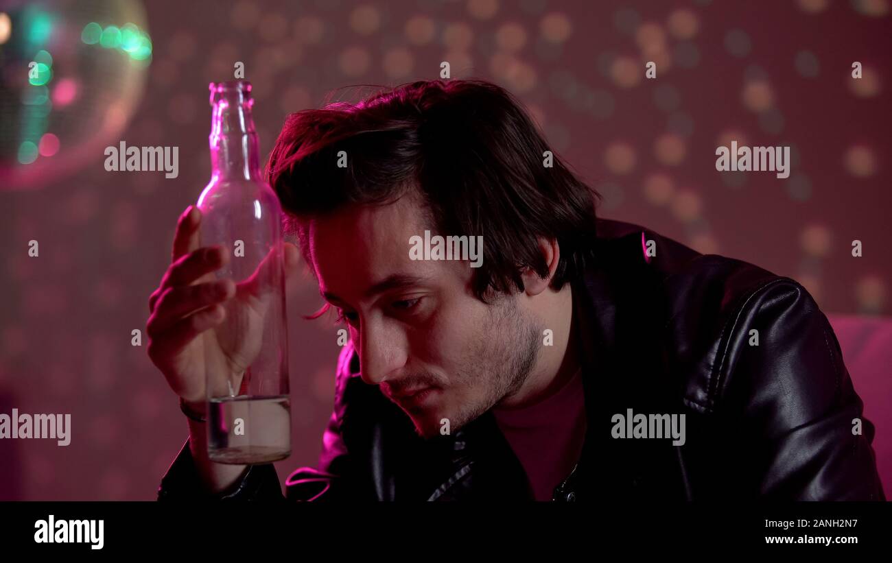Man holding vodka bottle, trying to escape problems using alcohol, addiction Stock Photo