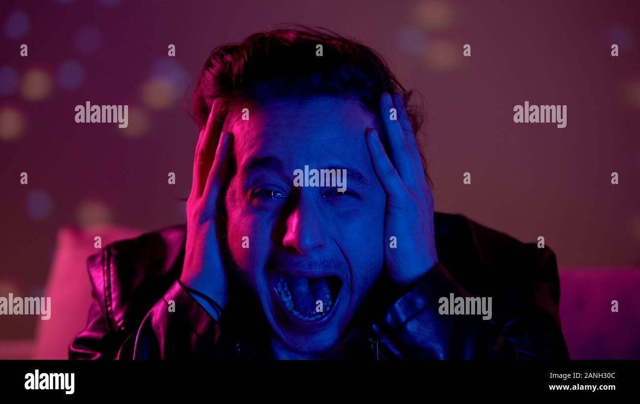 Terrified drunk young man crying and screaming at party, addiction