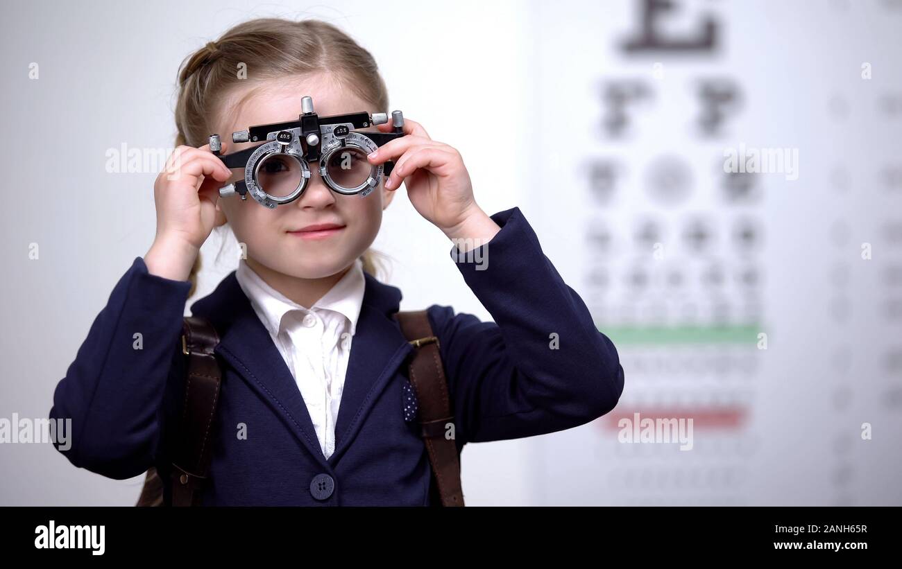 Schoolgirl putting optical trial frame to determine visual acuity, optometrist Stock Photo