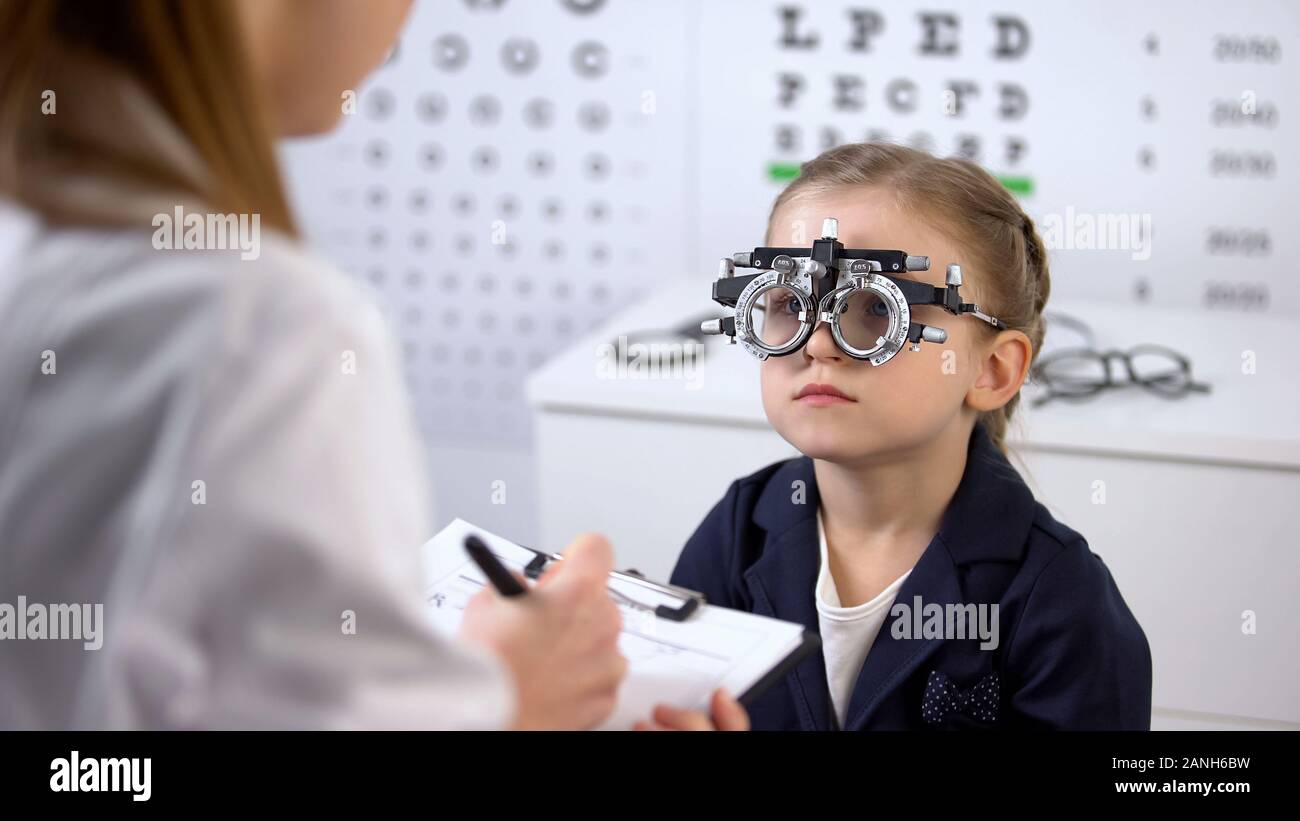 Cute girl in optical trial frame waiting prescription from ophthalmologist Stock Photo