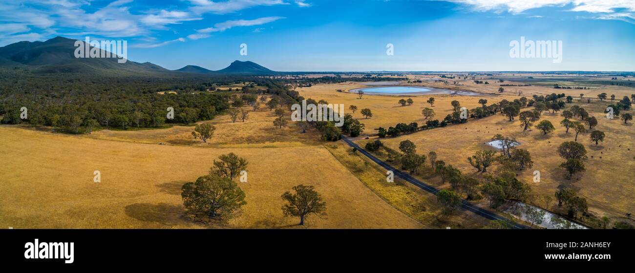 Victoria Valley Road passing through grasslands towards mountains in Australia Stock Photo