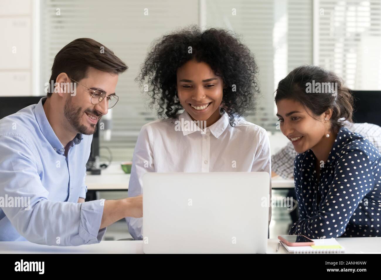 Multiracial smiling employees work together in coworking space using ...