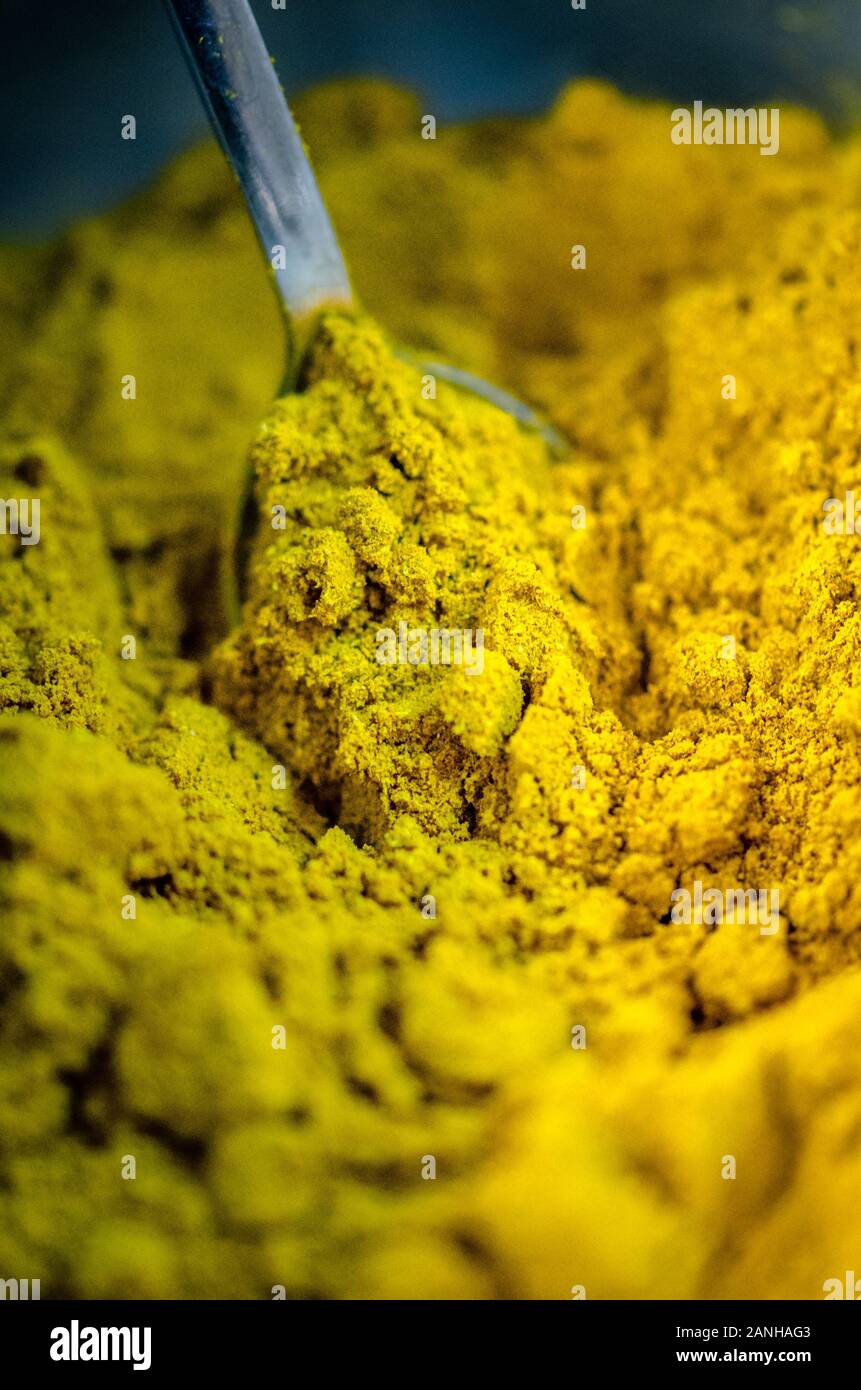 Full frame macro of yellow curry powder with a silver spoon picking it up Stock Photo