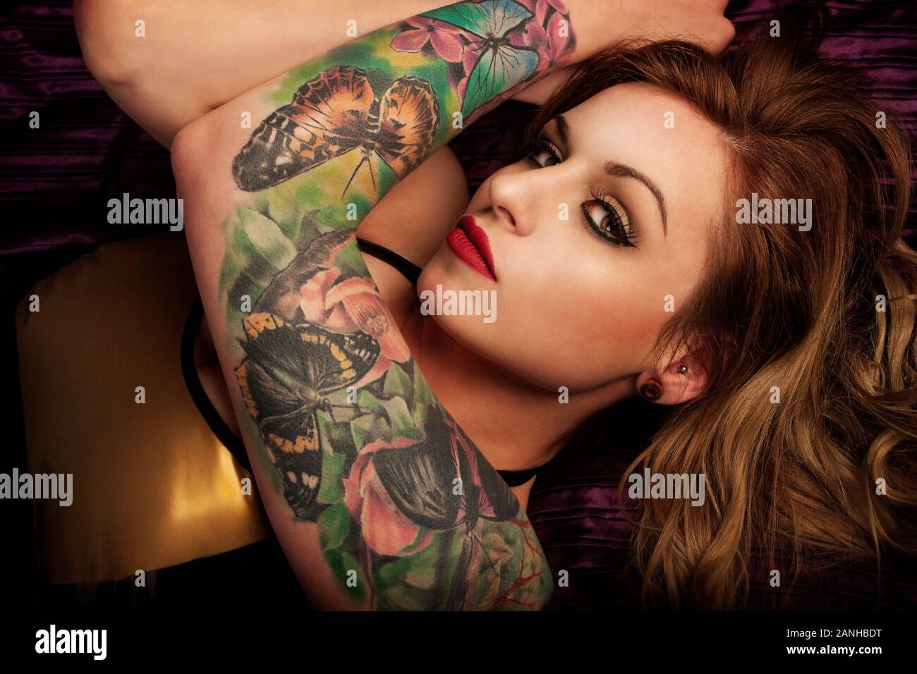 Beautiful blonde millennial young Caucasian woman 20s with a tattoo sleeve  / arm of butterflies in a gold latex dress. Model release available:KingaS  Stock Photo - Alamy