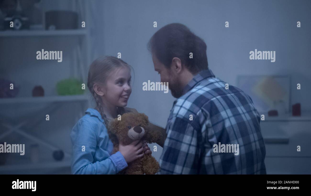 Happy girl with teddy looking with love at dad, trustful relations, tenderness Stock Photo