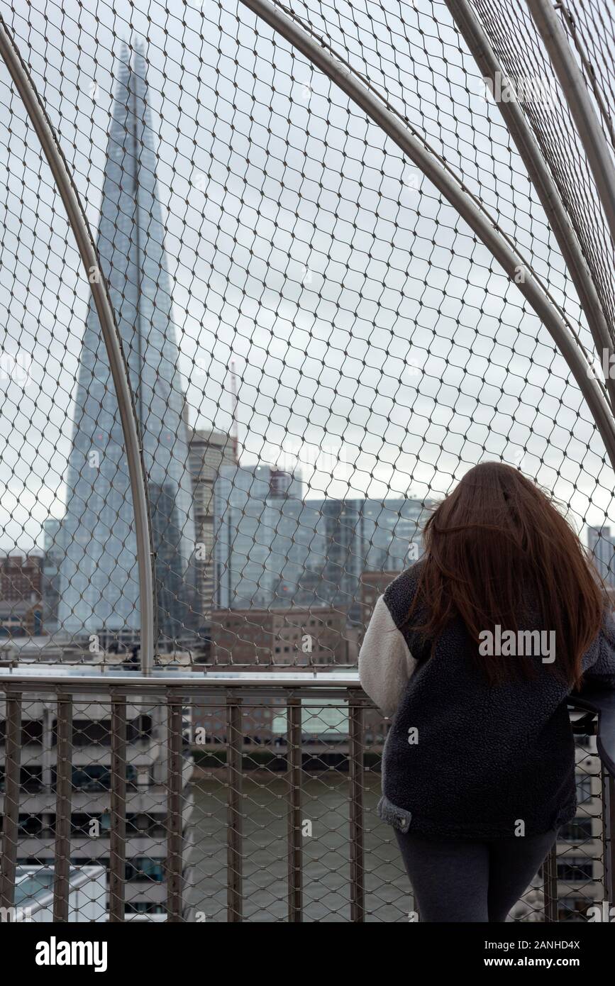 Lone young woman at the Monument London viewing platform enjoying the view over River Thames and The Shard building in London, UK Stock Photo