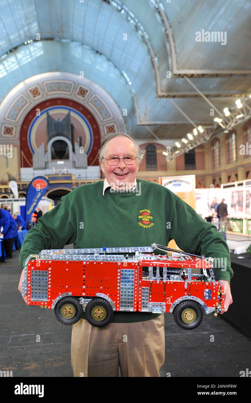 Warwick District Councillor and retired chartered Mechanical Engineer George Illingworth holding a Meccano model of a Royal Air Force Thornycroft Crash Tender Mk9 on the opening day of the London Model Engineering Exhibition, Alexandra Palace, London.   George is displaying 30 of his hand-built large 1/12 scale Meccano Fire Engines from his 60+ magnificent collection.  The collection is a visual history of the fire service and appliances over the last 100 years. His collection features fire trucks and appliances from the early 1800s when the first organised municipal fire brigade in the world Stock Photo