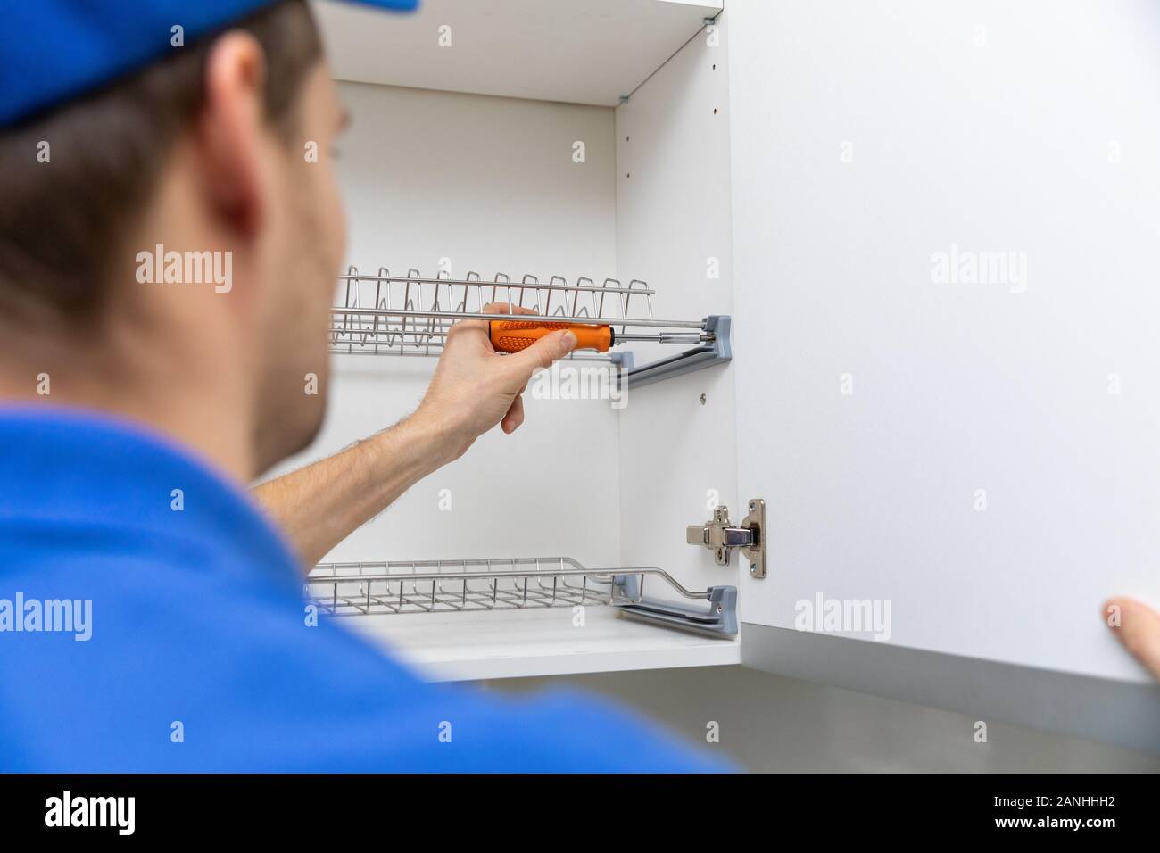 furniture service worker screwing kitchen dish rack Stock Photo