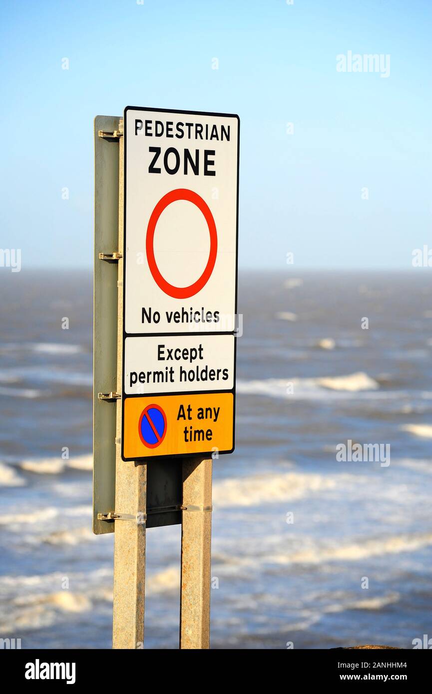 Pedestrian zone sign in front of choppy sea at high tide during a storm Stock Photo