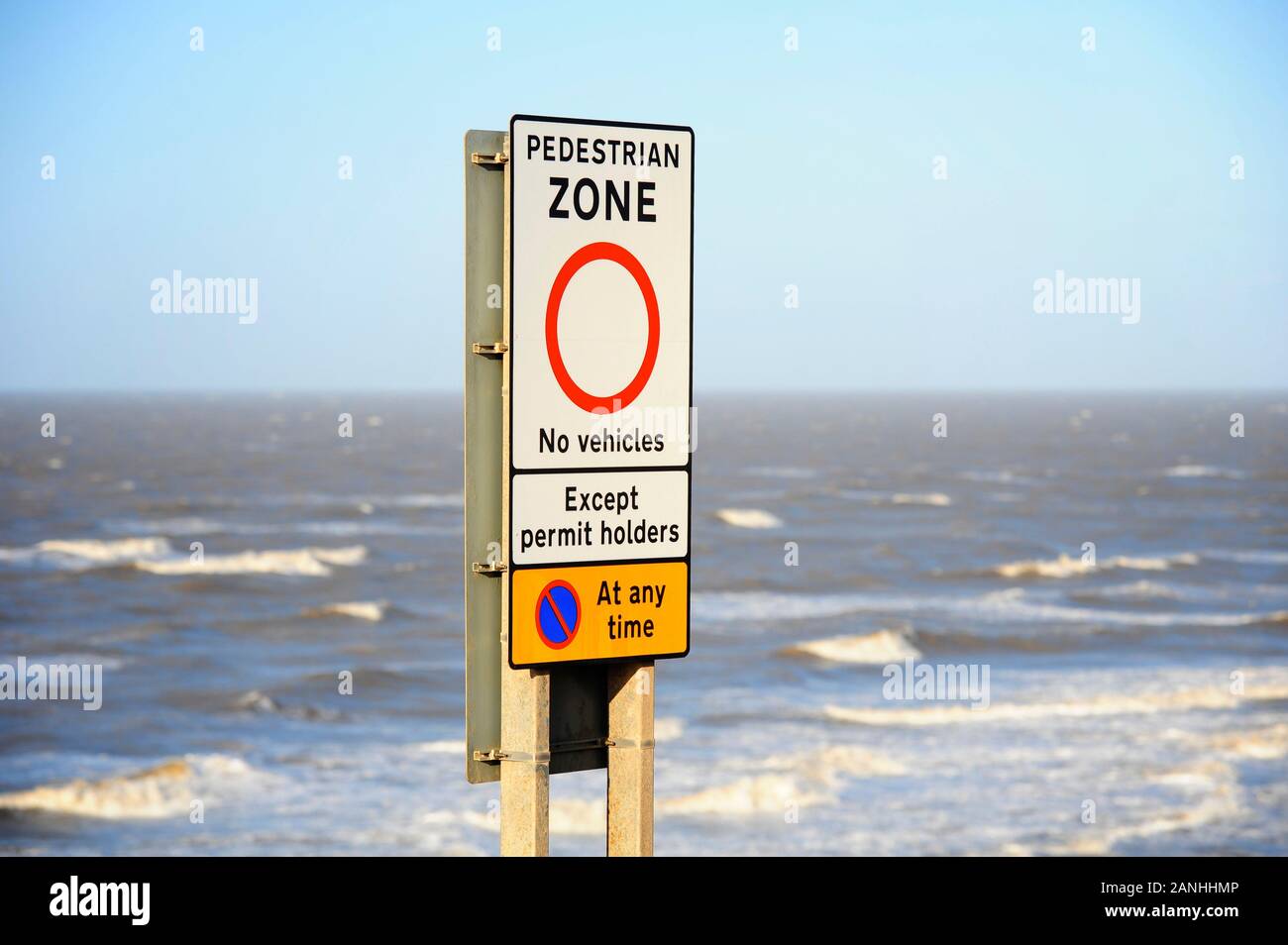 Pedestrian zone sign in front of choppy sea at high tide during a storm Stock Photo