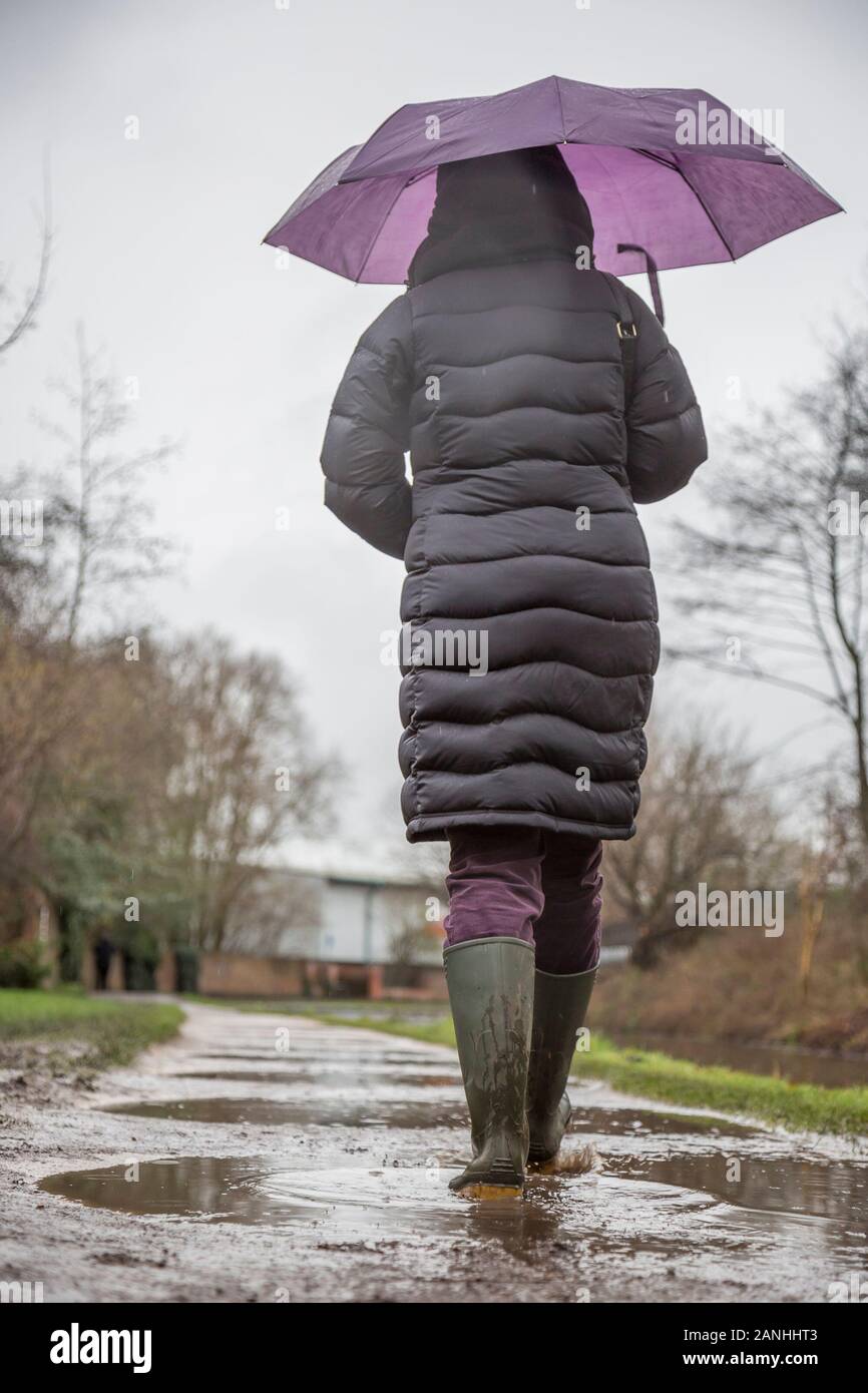 Kidderminster, UK. 17th January, 2019. UK weather: with absolutely no let up in the wet weather, water levels are on the rise and even pavements are flooded forcing pedestrians to resort to their wellington boots. A woman with umbrella, low angle and rear view, is seen here isolated walking through the puddles in her wellies along a canal towpath in the rain. The month of January is proving to be a wet, dreary start to the new year. Credit: Lee Hudson/Alamy Live News Stock Photo