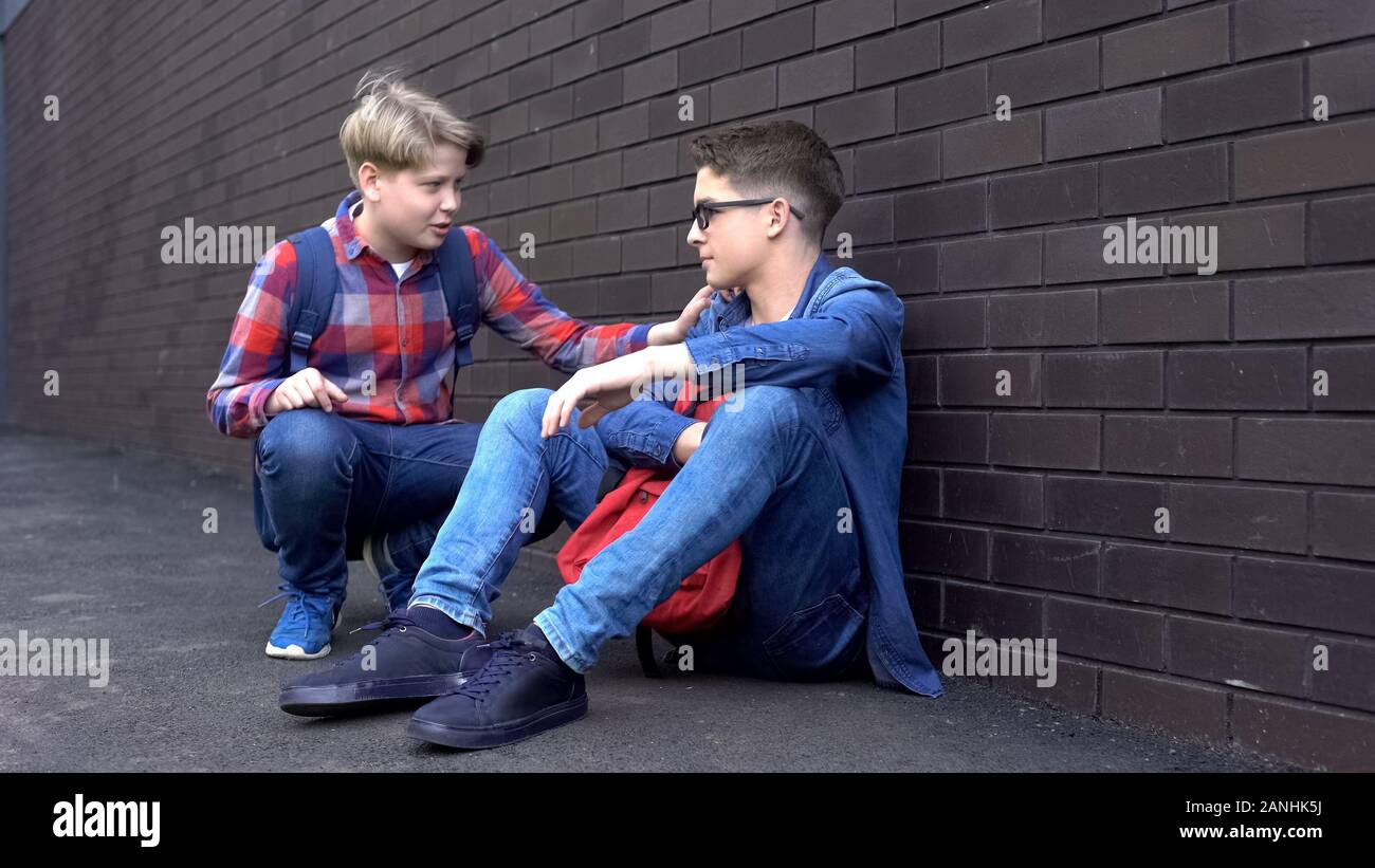 Kind teenage boy starting friendship with bullied student, helpline for children Stock Photo