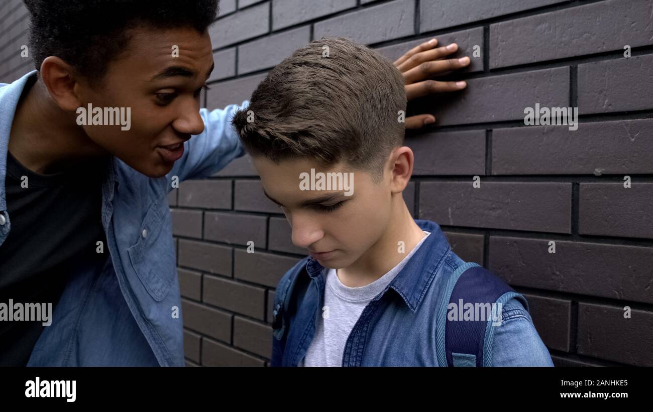 Mean african american student mocking weak boy, psychological abuse, threat Stock Photo