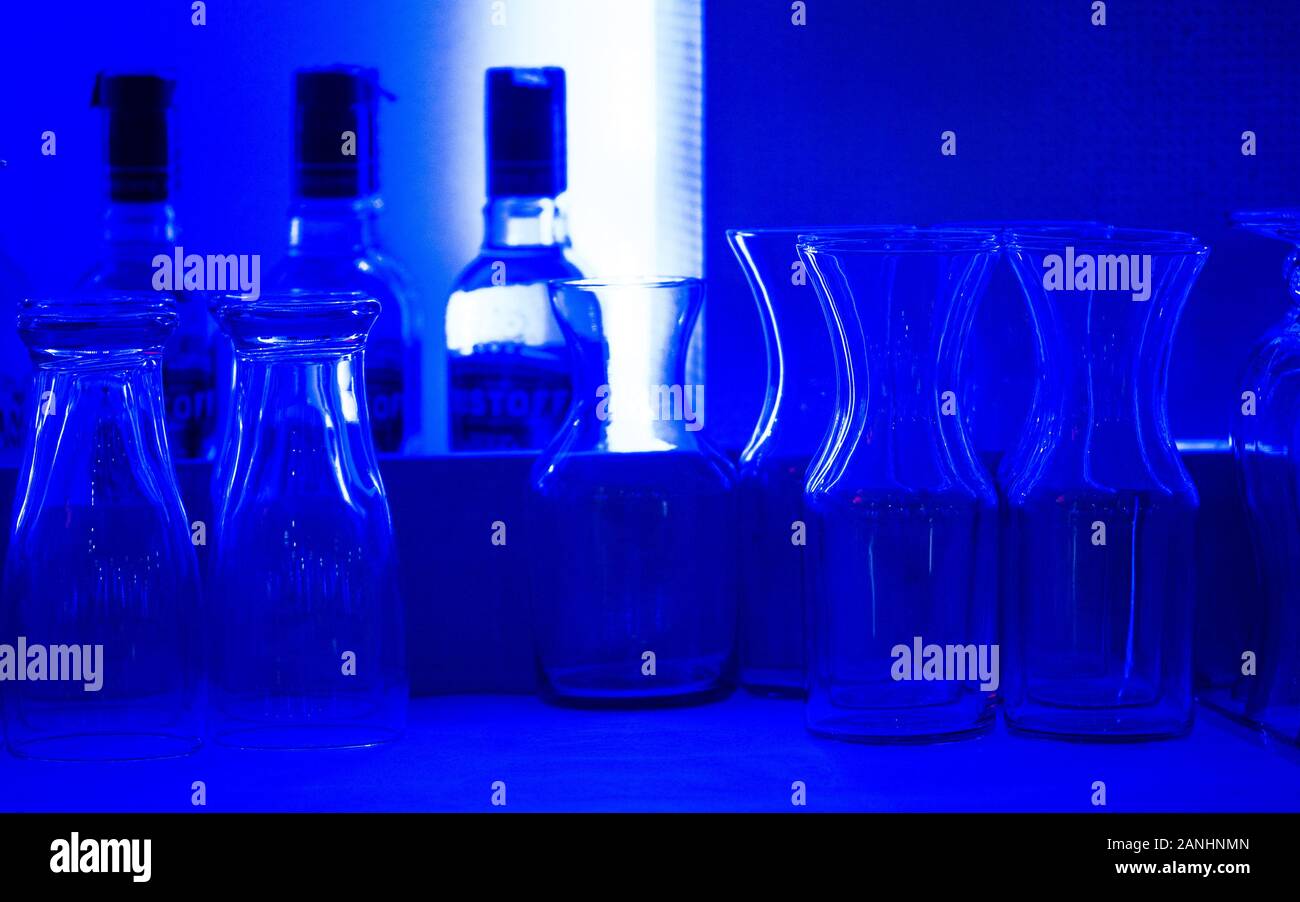 Blue Bar. Glasses lined up on the back of a contemporary bar under a blue light. Stock Photo