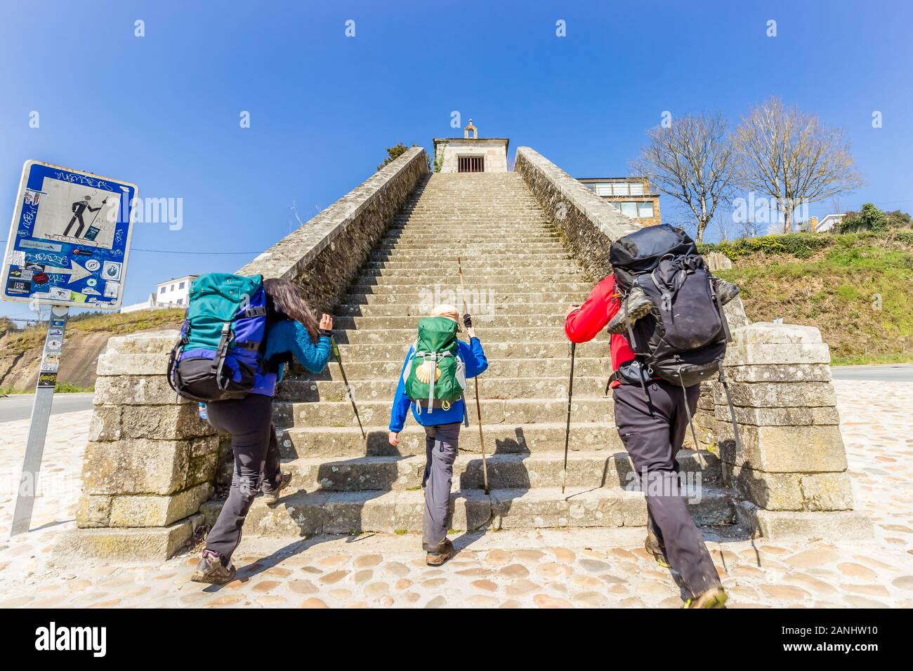 Two Adults and Child Pilgrims Ascending Stairs at City Entrance to Portomarin, along the Way of St James (Camino de Santiago) Stock Photo