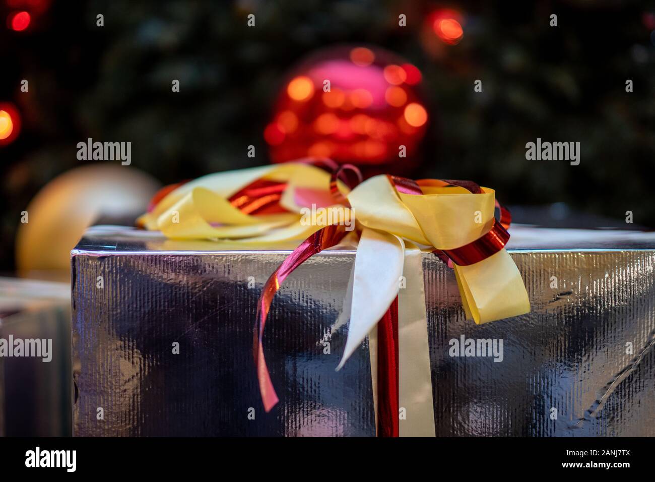 gift in a box under the Christmas tree with a ribbon bow Stock Photo