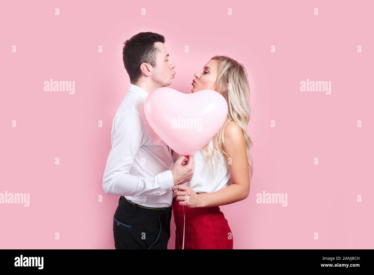 Couple covering faces with balloon on pink background Stock Photo