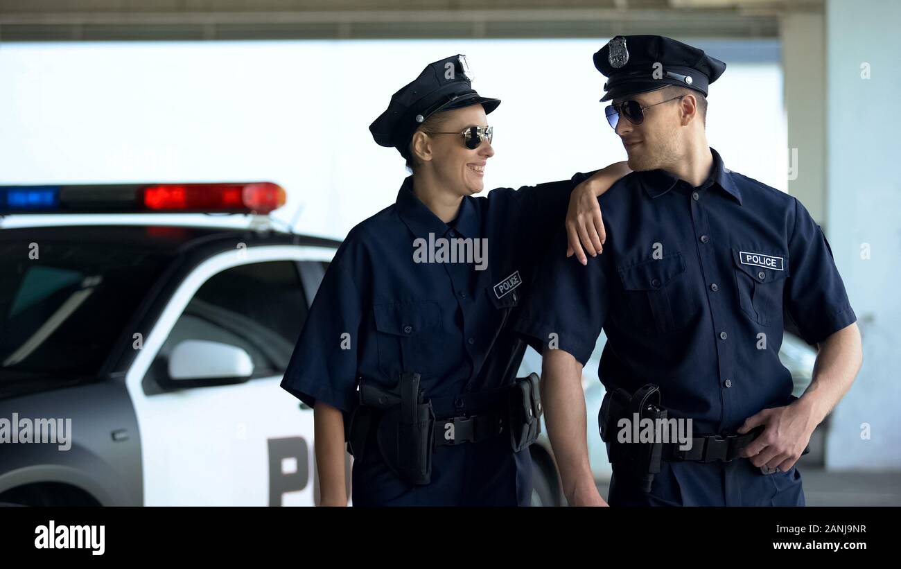 Positive police officers in uniform and glasses smiling together, law and order Stock Photo - Alamy