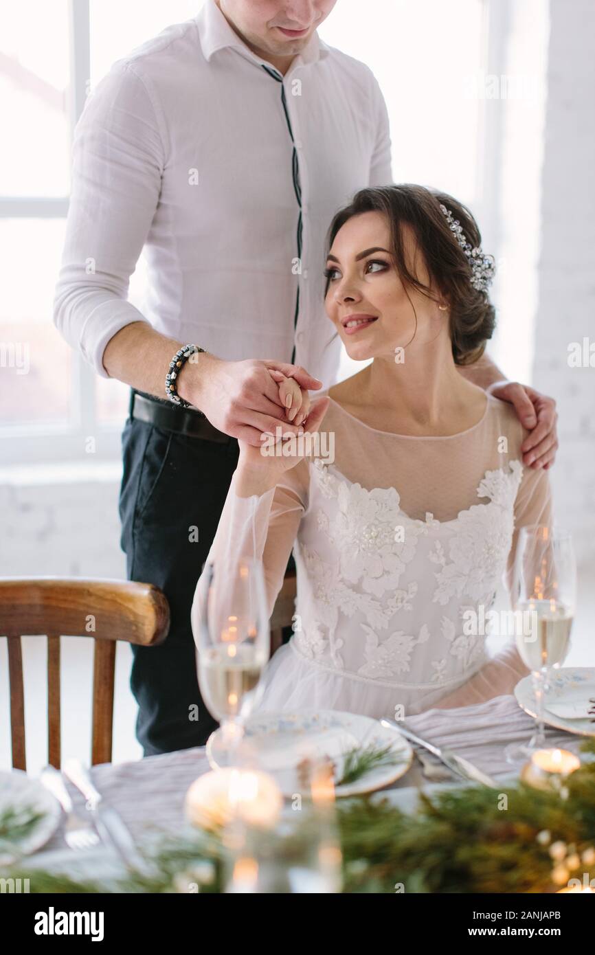 pretty bride and groom near wedding table with wedding cake, blue candles and pine decorations Stock Photo