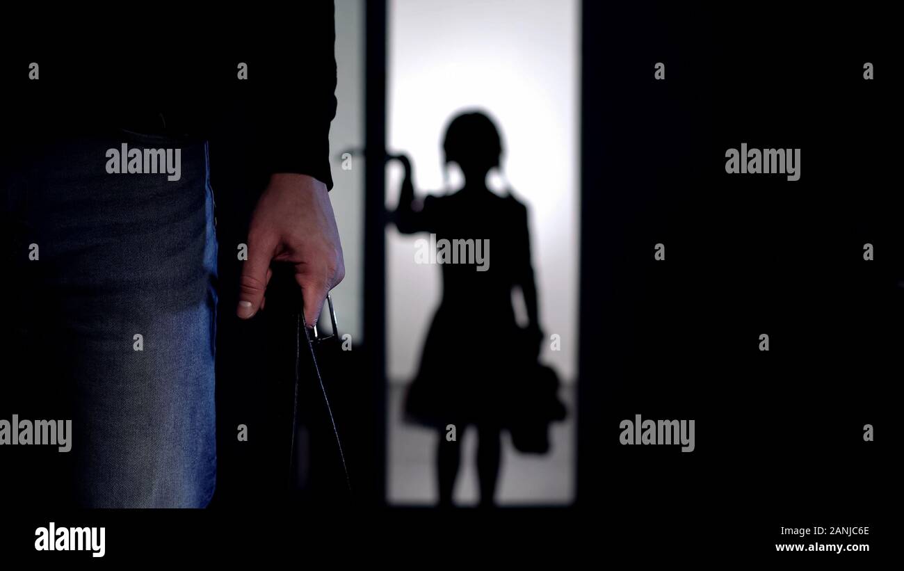 Silhouette of little girl entering room, violent father with belt on foreground Stock Photo