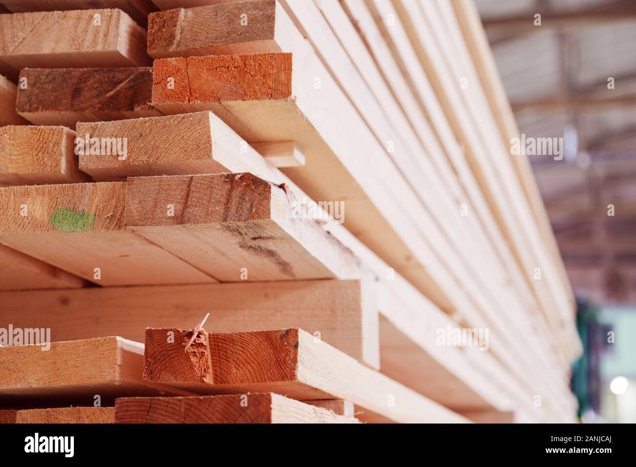 Warehouse or factory for sawing boards on sawmill indoors. Wood timber stack of wooden blanks construction material. Logging Industry. Stock Photo