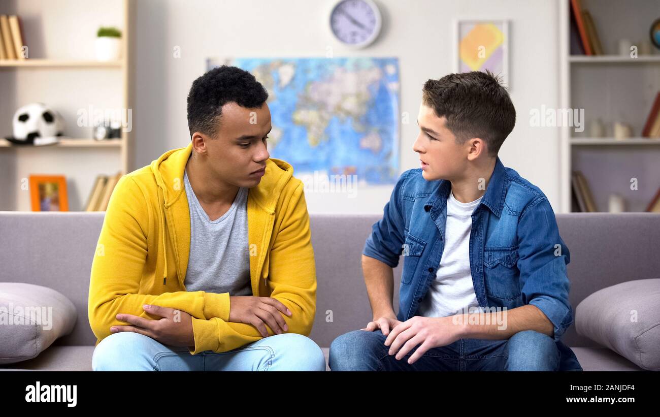 Afro-American teen boy sharing problems with Caucasian friend, bullying problem Stock Photo