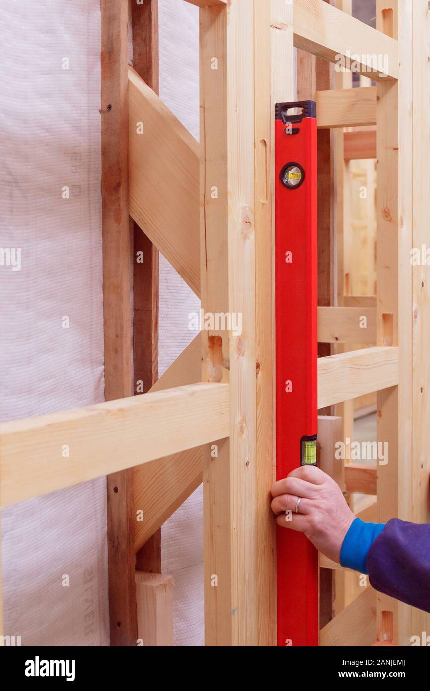 Quality control of the construction of wooden building structures of a frame house. Measurement of vertical deviation of installed structures. Stock Photo