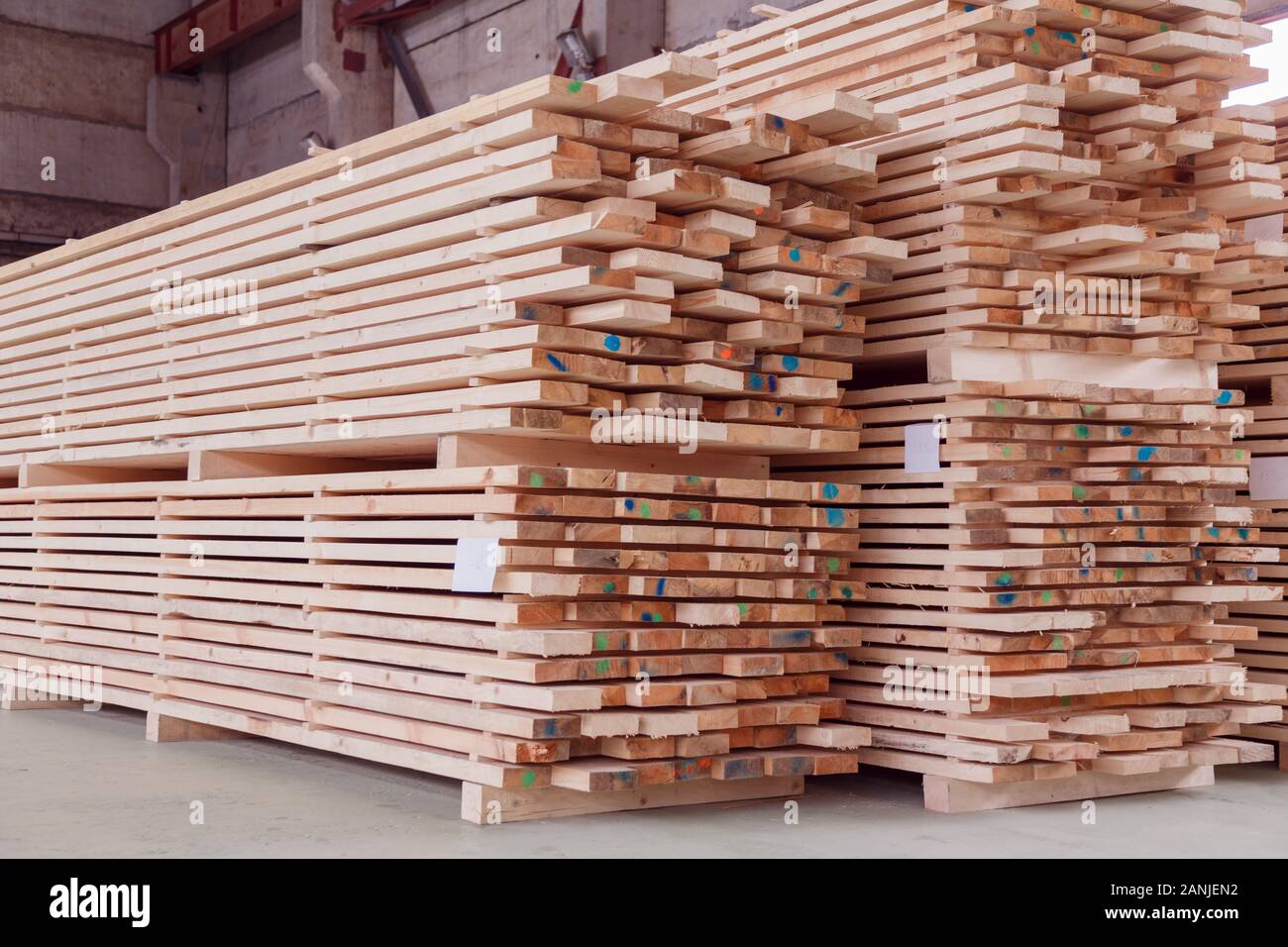 Warehouse or factory for sawing boards on sawmill indoors. Wood timber stack of wooden blanks construction material. Logging Industry. Stock Photo