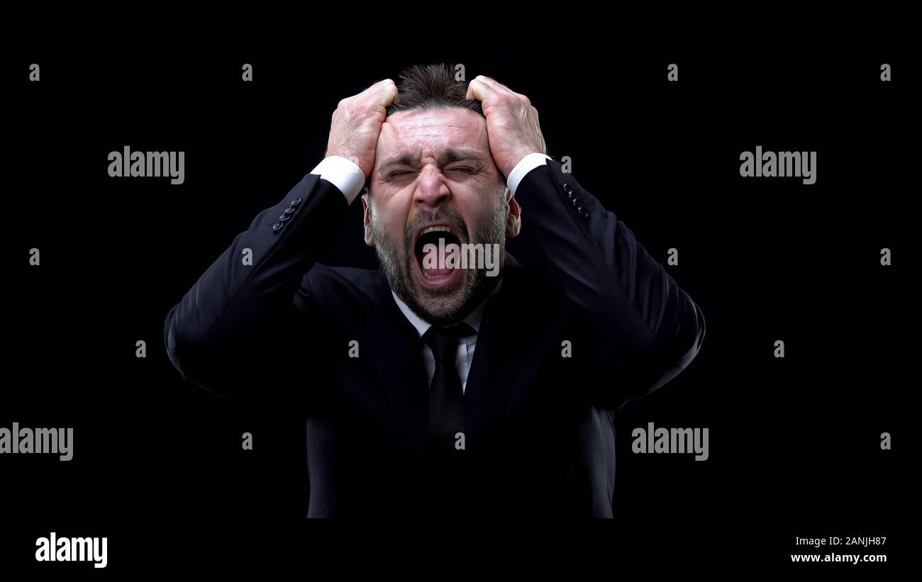 Worried businessman shouting on dark background, mental exhaustion, pressure Stock Photo