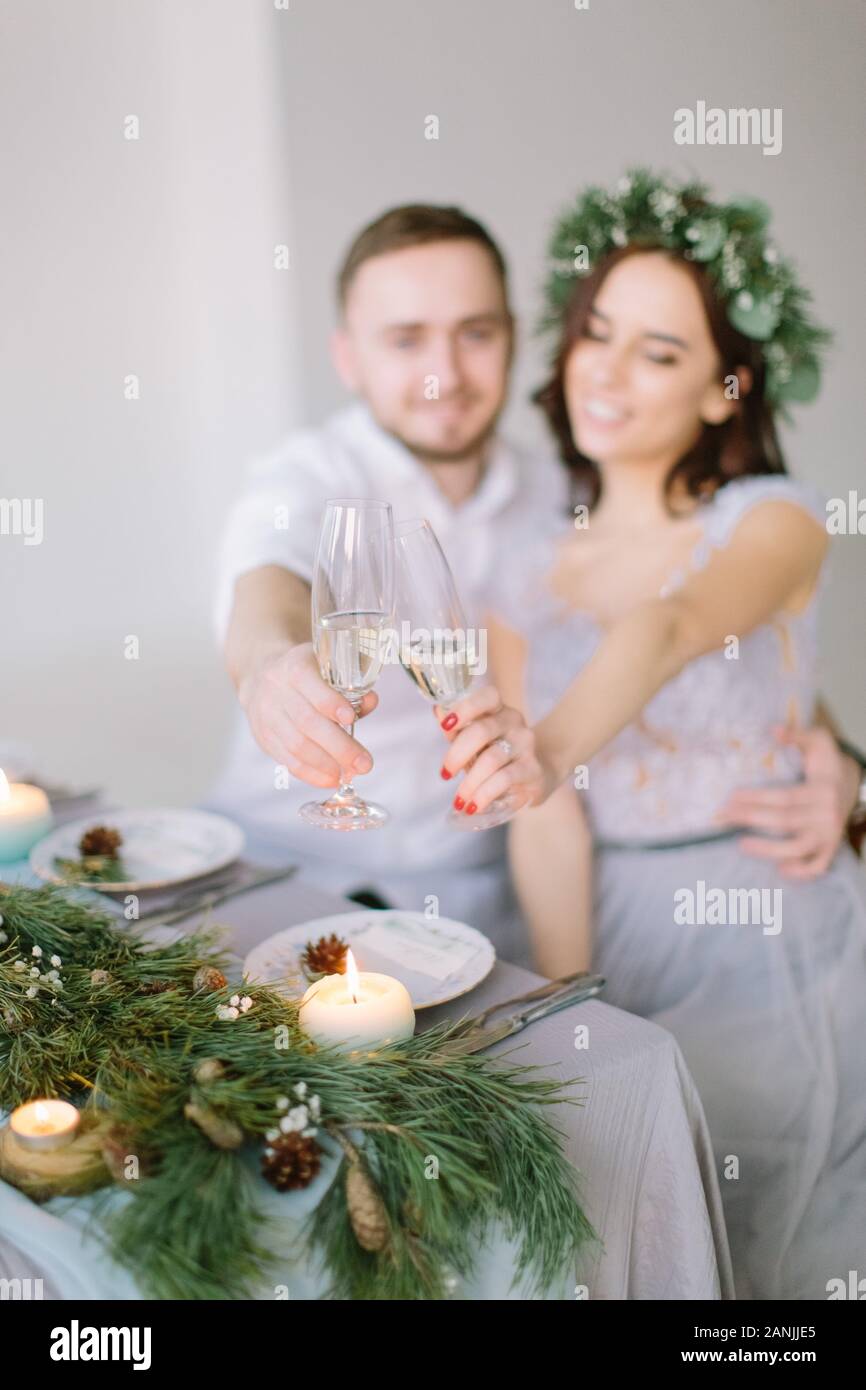 Happy bridesmaid and groomman at the wedding table drink champagne. Group of people sitting at wedding table in the white hall decorated with pine Stock Photo