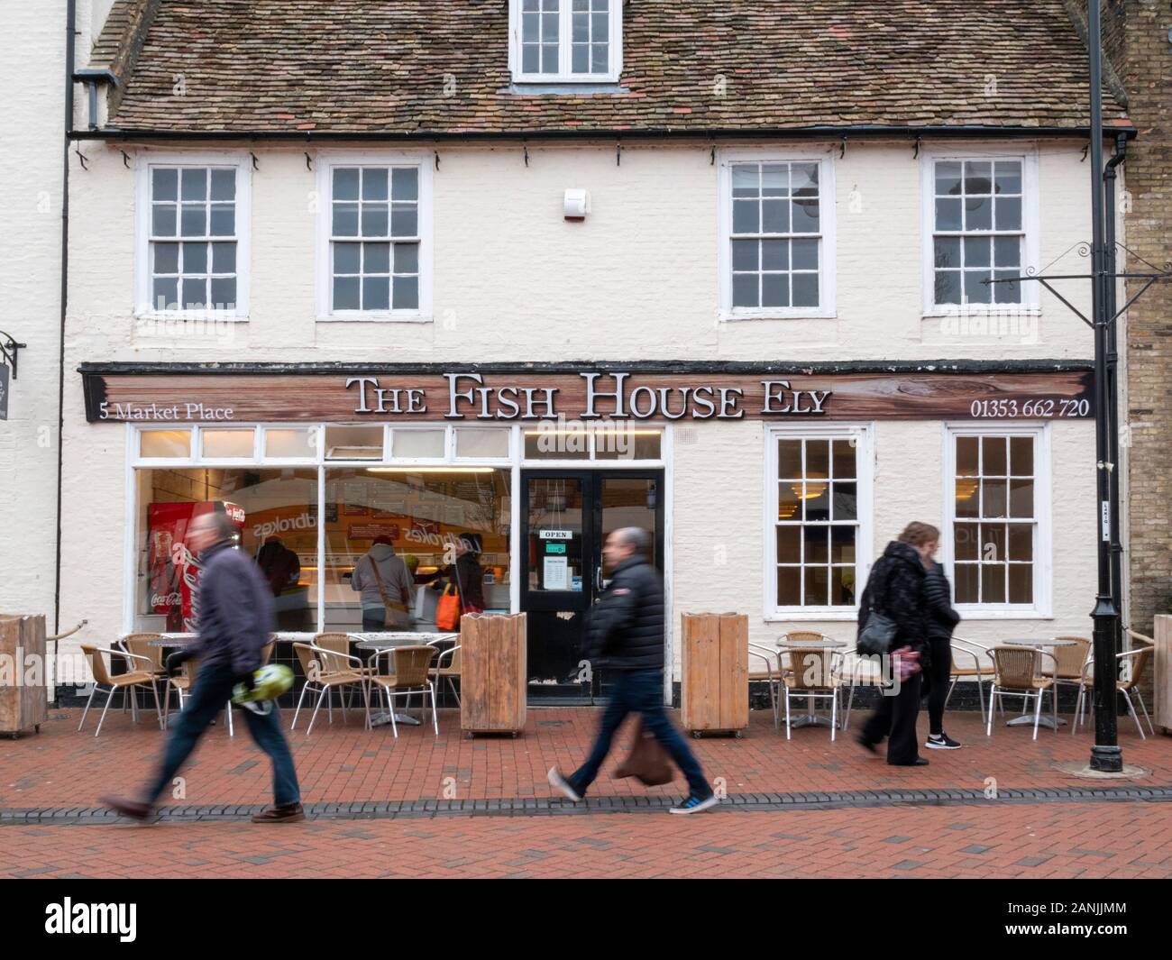 People walk past the Fish House Ely fish and chip shop in Ely Cambridgeshire UK Stock Photo