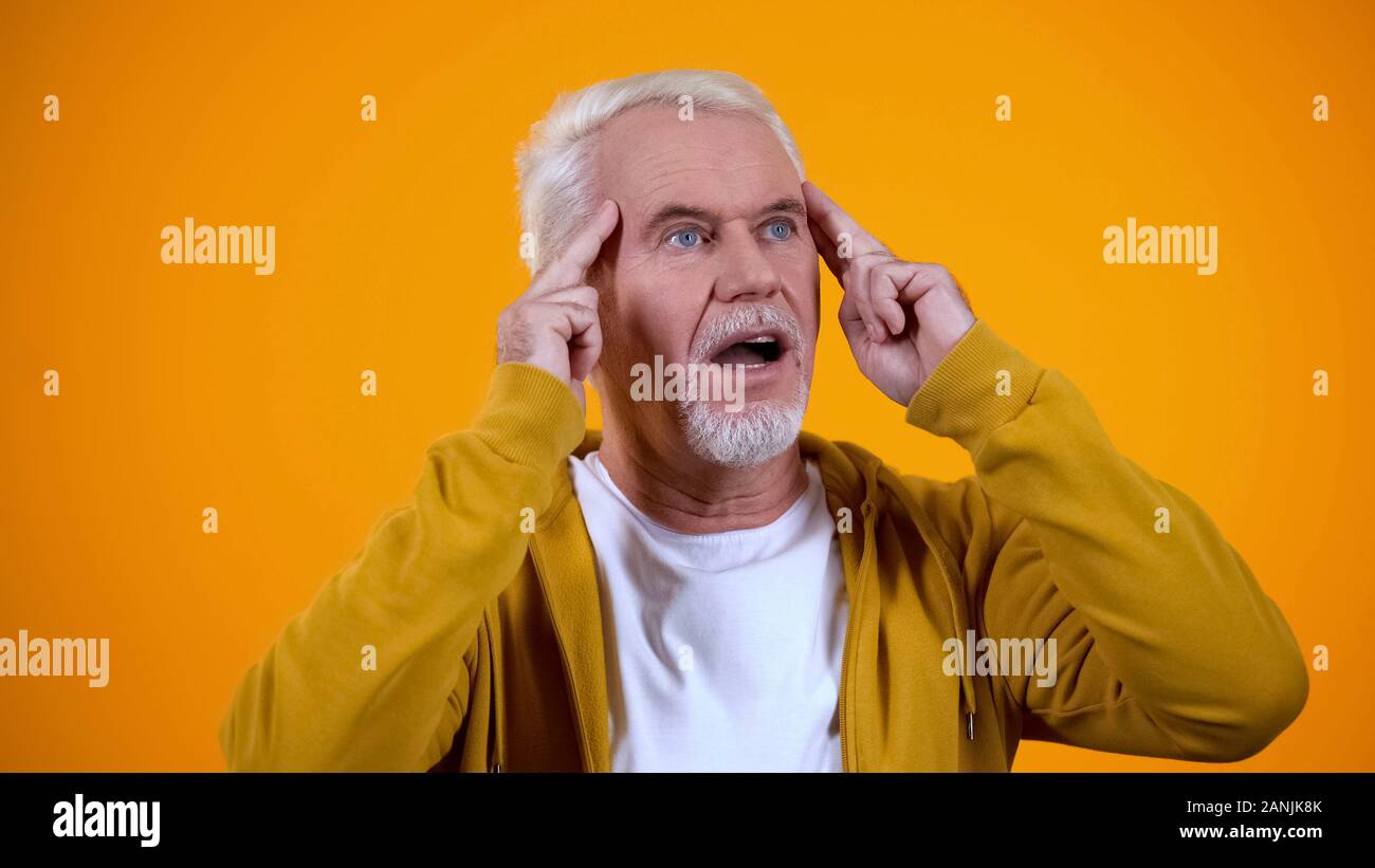 Pleased aged magician touching temples, developing telepathic mind abilities Stock Photo