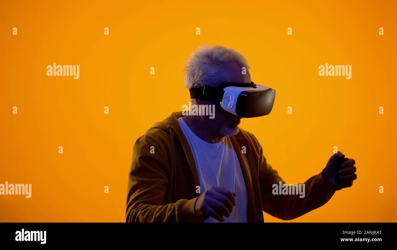 Male pensioner in virtual reality goggles playing videogame, modern technologies Stock Photo
