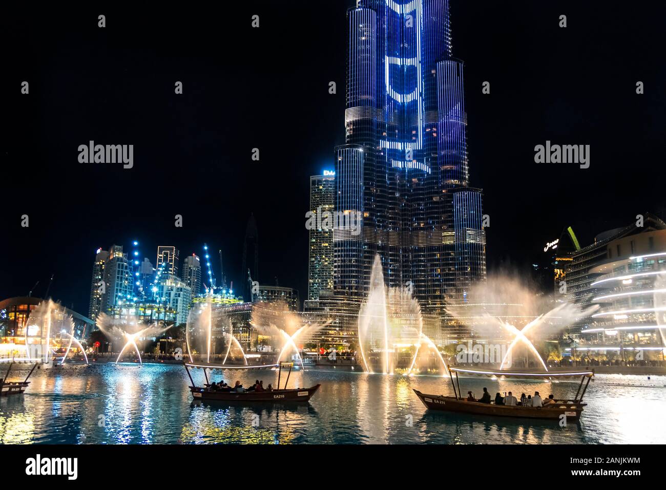 The Dubai Fountain display illuminated at night with tour boats in front of choreographed fountains in the Burj Khalifa Lake, Dubai, UAE Stock Photo