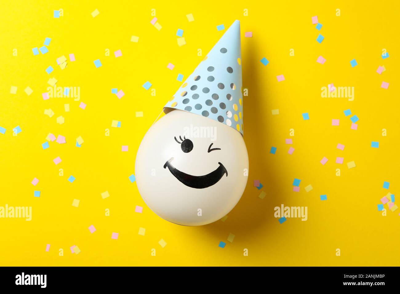 Balloon with happy face on decorated yellow background, top view Stock