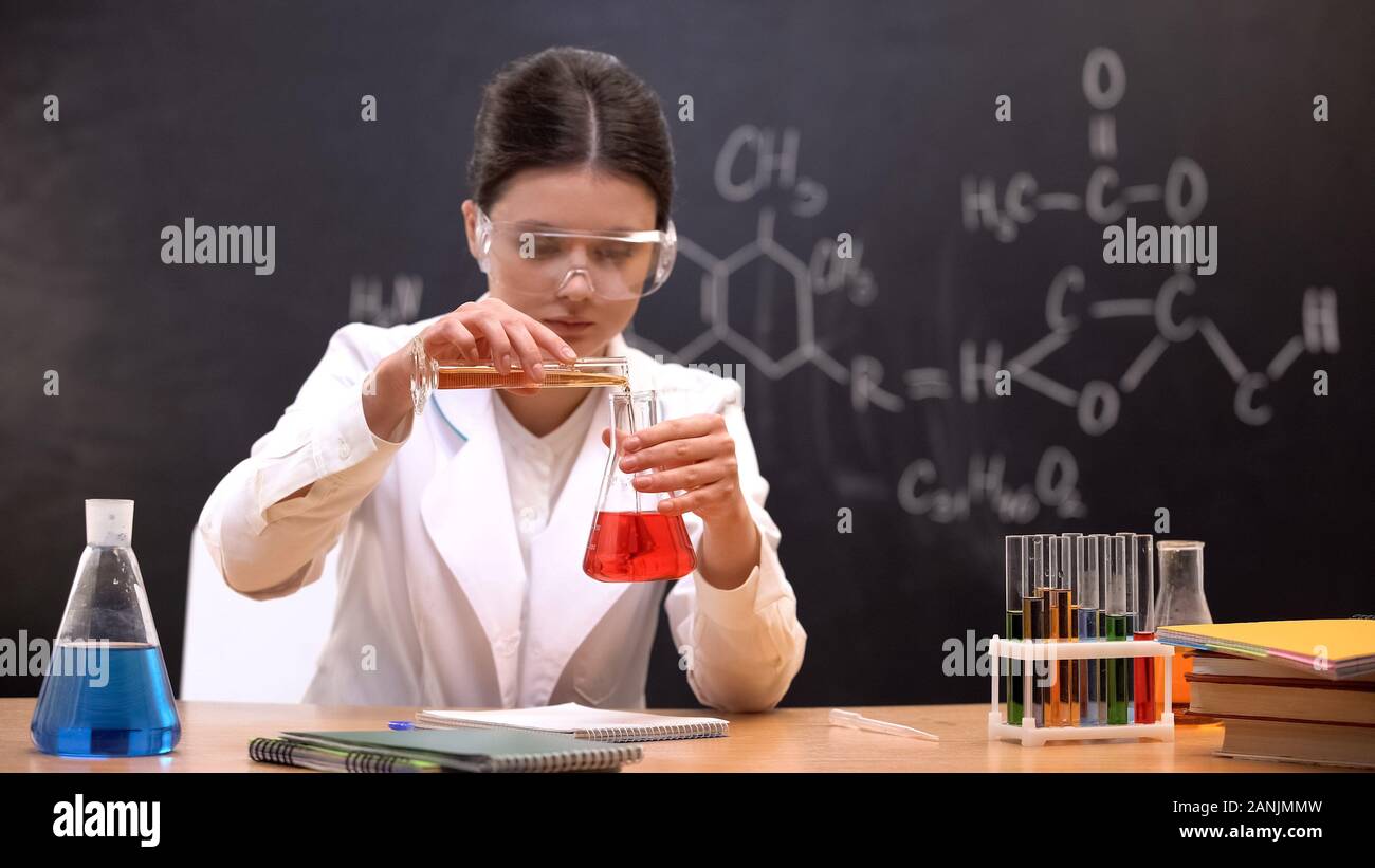 Chemistry student mixing liquids in scientific laboratory, conducting