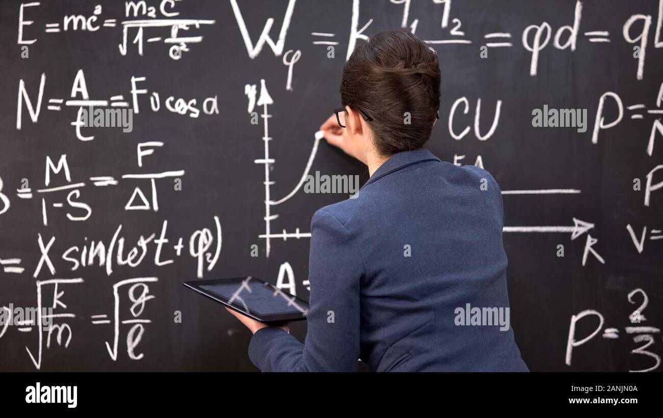 Female teacher drawing graph on chalkboard and holding tablet