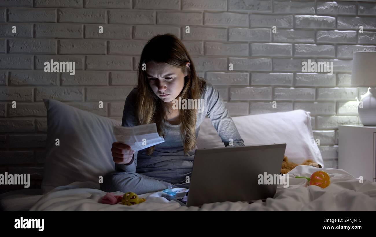Young mother reading pills instruction, sitting among toys, treating ill child Stock Photo