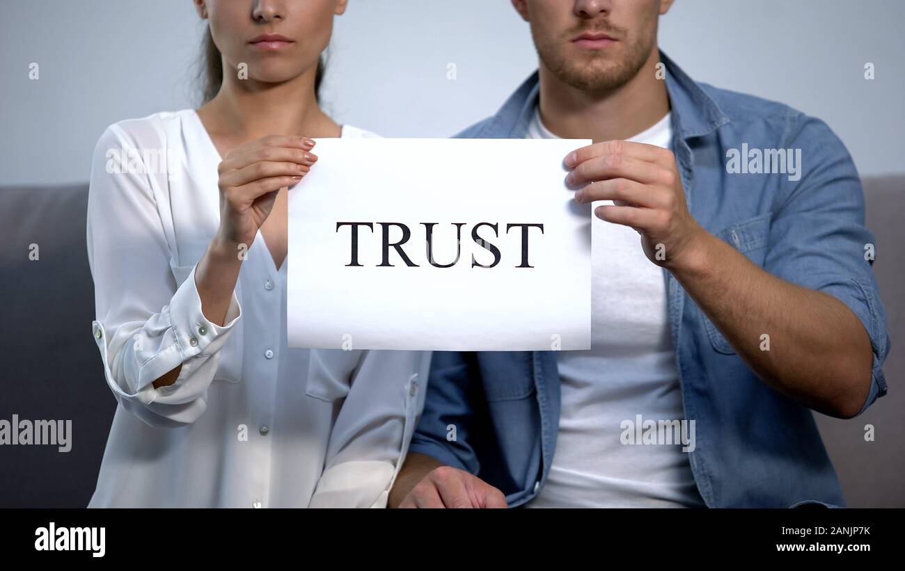 Serious couple holding cardboard with trust word, family relationship, attitude Stock Photo