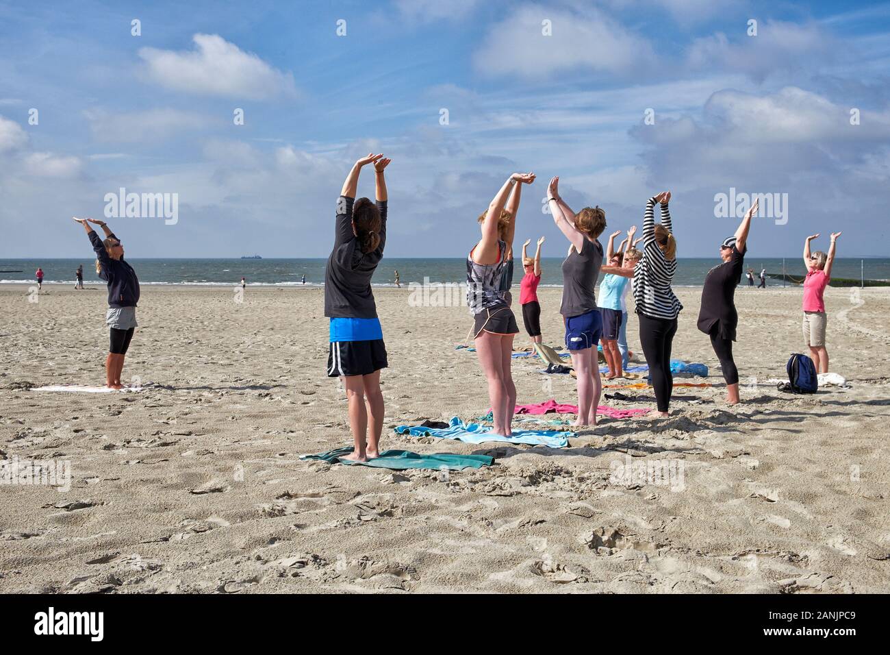 Female yoga practitioner giving a yoga lesson to a group of woman on the south beach at Borkum island Stock Photo
