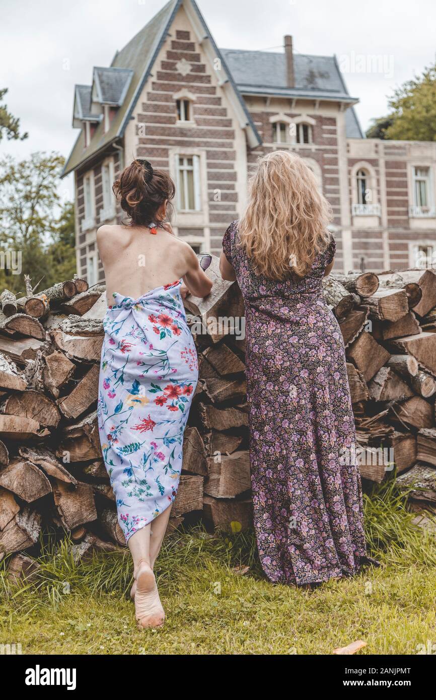 couple of mature friendly women on vacation watching an amazing historic building from a woodpile. out in nature Stock Photo