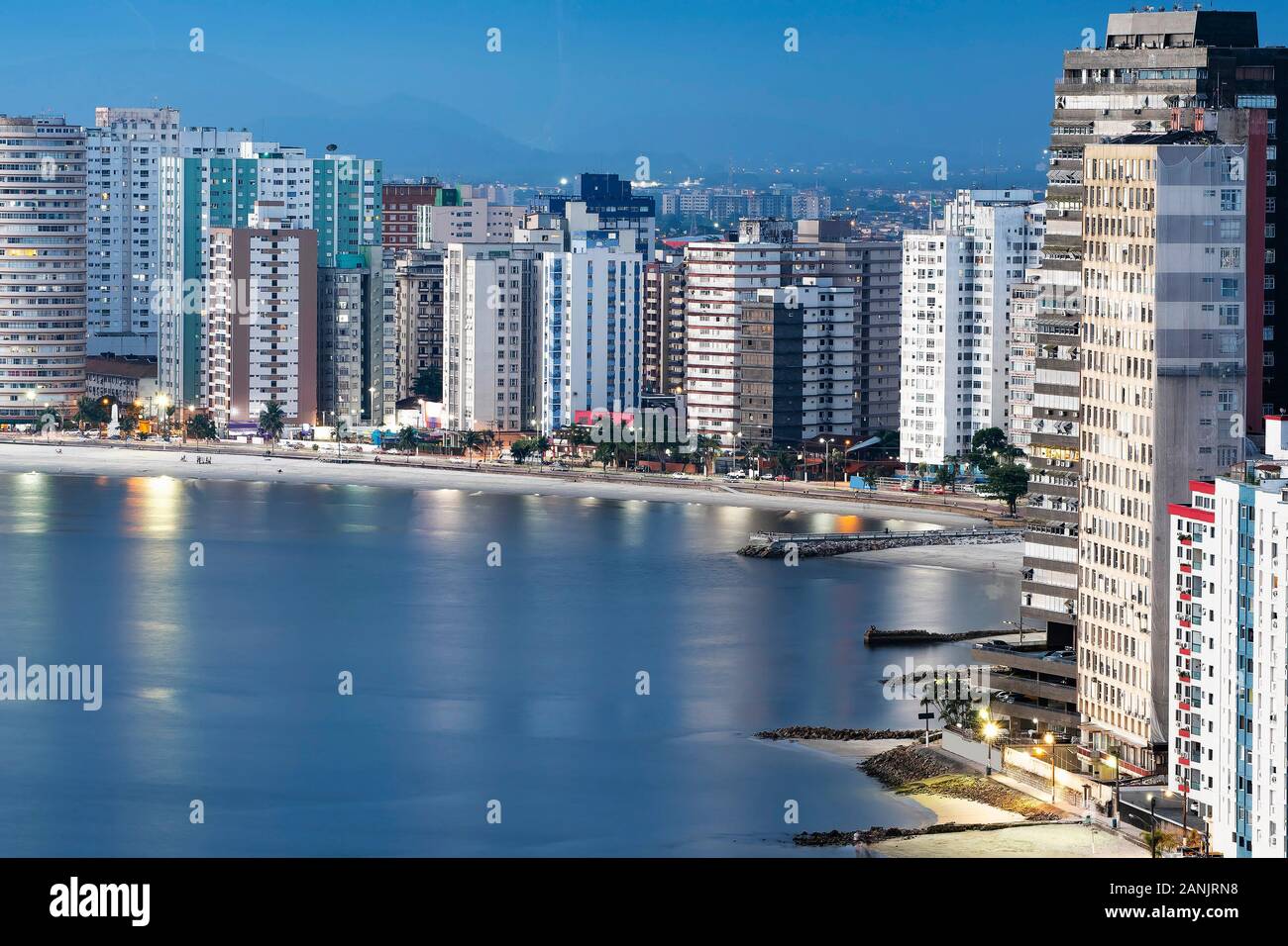 Urbanized coast, tall buildings near to the beach of a coastal city at dusk, when city lights begin to turn on. Paulista coast, Sao Vicente city - SP Stock Photo