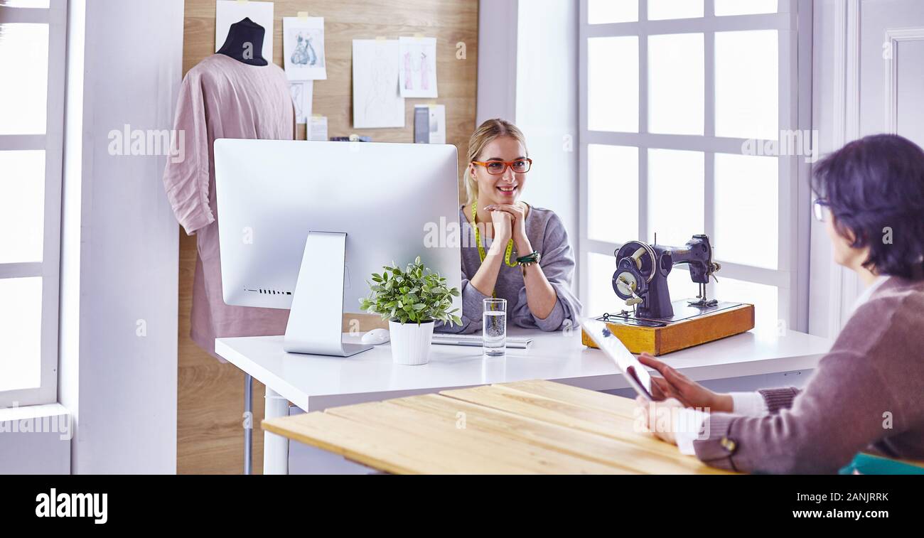 pretty dressmaker showing a new design to her client Stock Photo - Alamy