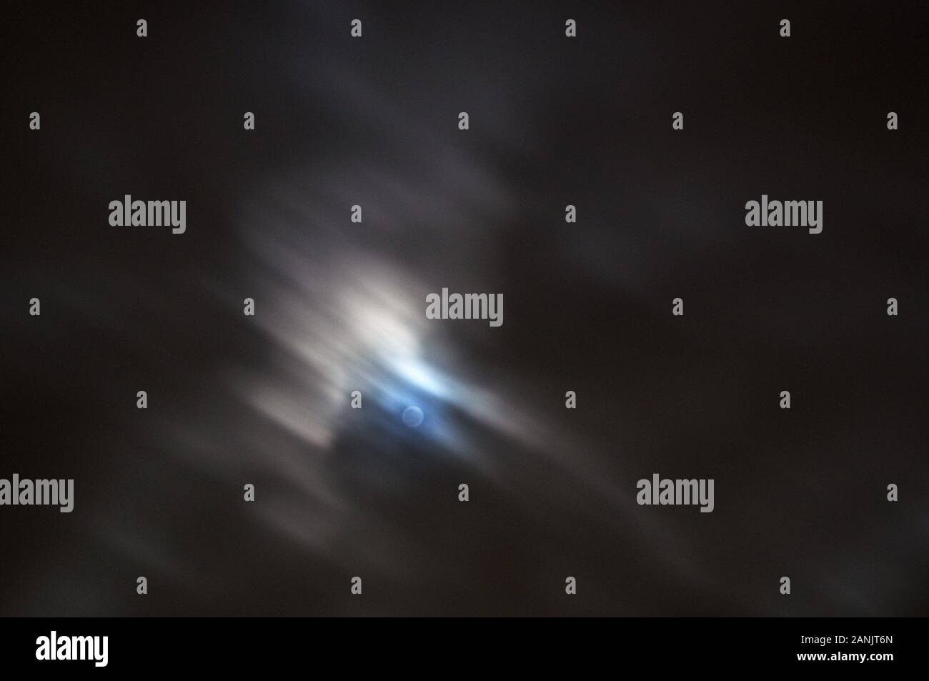 A bright full moon with fast moving wispy clouds creating abstract background, clouds are lit by moonlight. Stock Photo