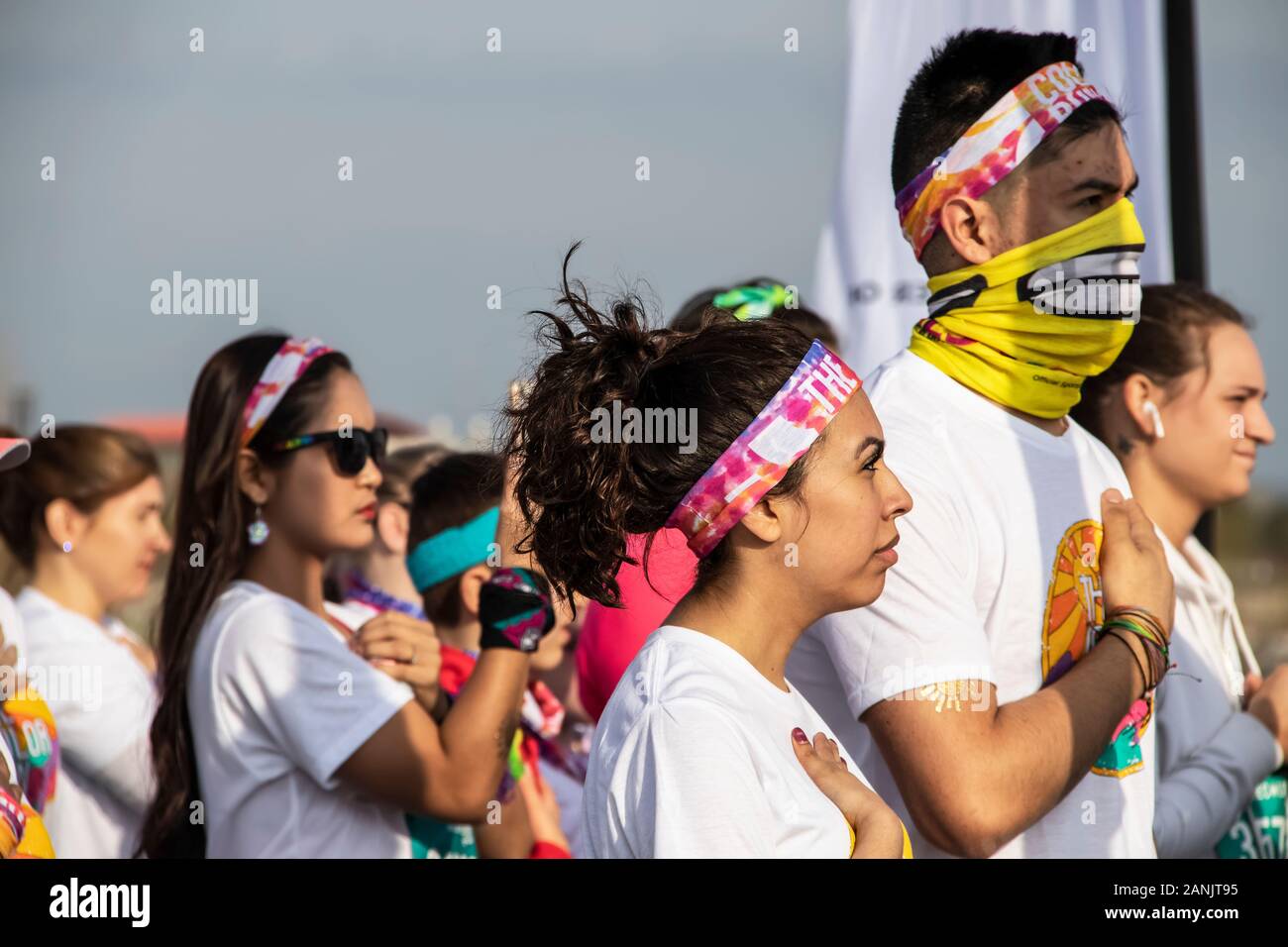 4-6-2019 Tulsa USA Woman dressed for Color Run puts hand over heart during playing of National Anthem with crowd around - selective focus Stock Photo