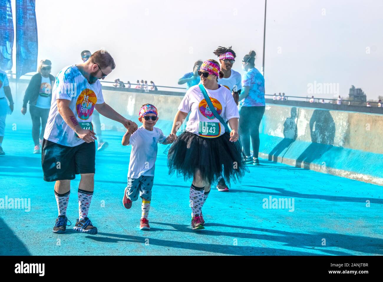 https://c8.alamy.com/comp/2ANJTBR/april-6-2019-tulsa-usa-family-of-mother-father-and-little-boy-in-matching-costumes-all-holding-hands-and-laughing-in-color-holi-run-blue-powder-s-2ANJTBR.jpg