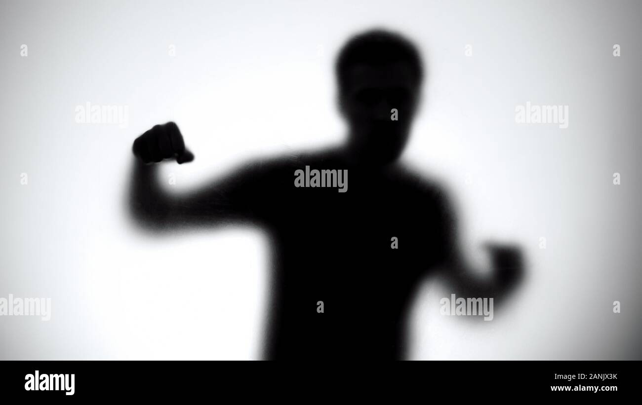 Silhouette of man behind glass attacking enemy, anonymous fight club, athlete Stock Photo