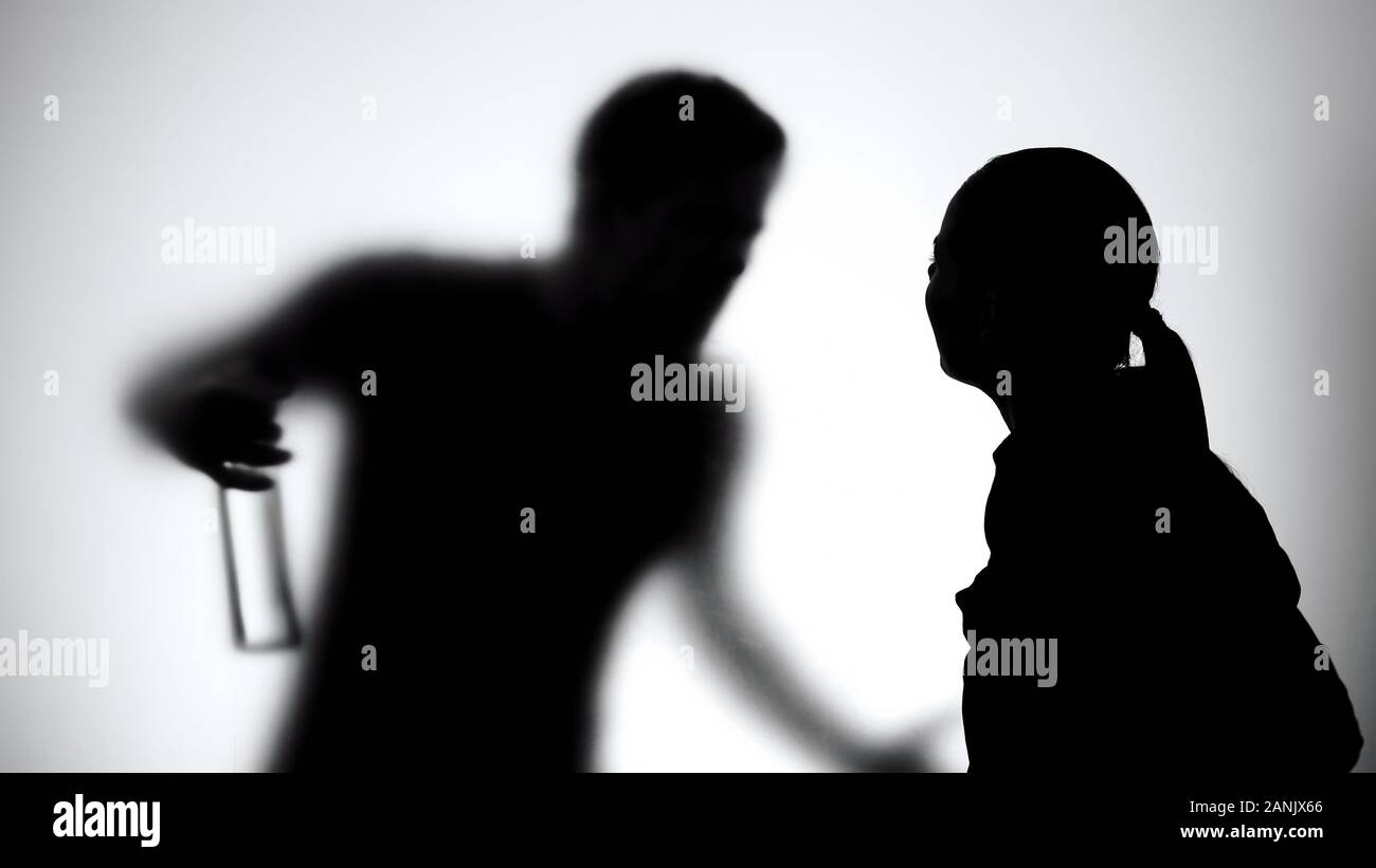 Silhouette of wife and husband quarreling, man holding alcohol bottle, addiction Stock Photo